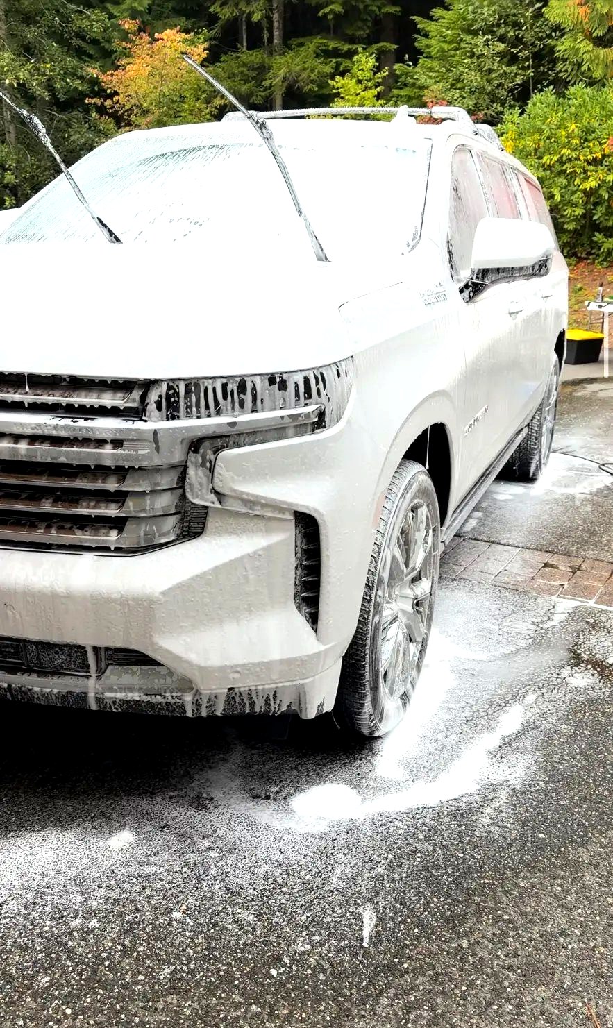 White Chevy Suburban covered in thick snow foam during the pre-wash