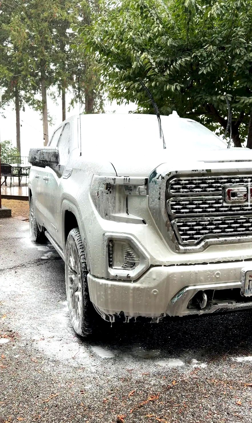 GMC Sierra pickup blanketed in snow foam on a driveway