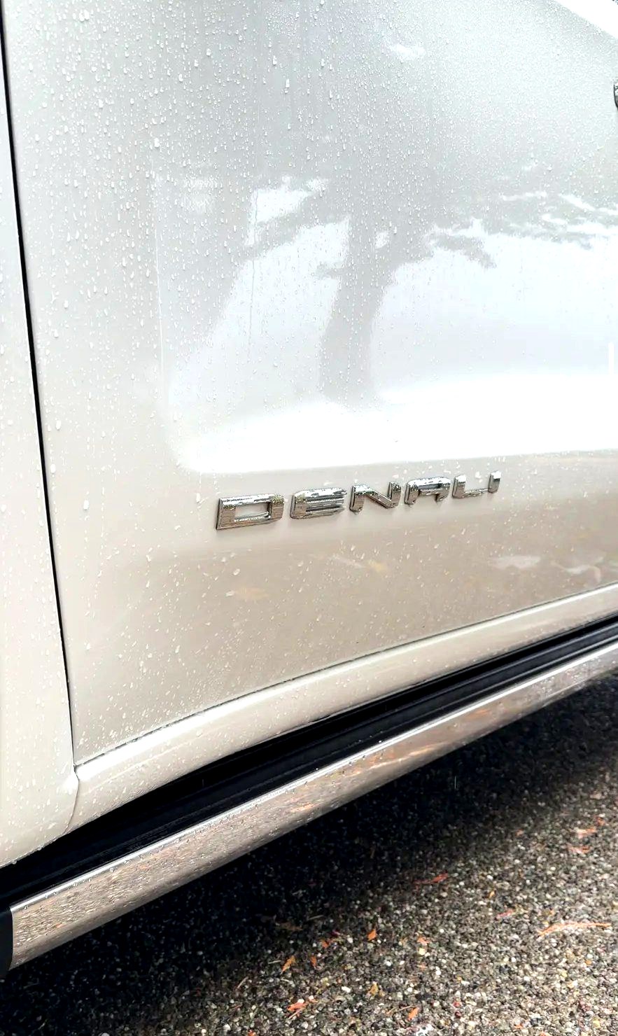 Water beading on the clean door of a GMC Denali next to the Denali badge